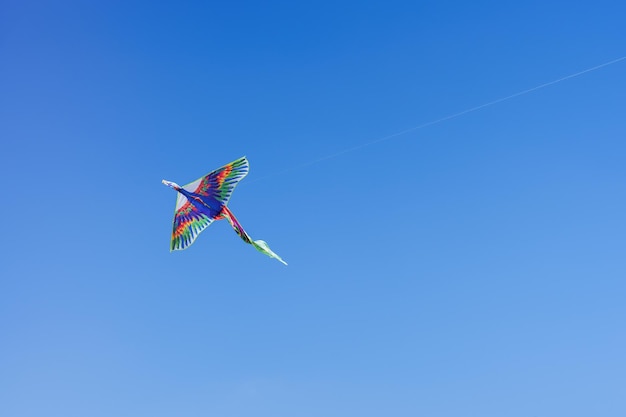 Colorful kite soars high in the sky Blue sky Sports kite festival Clean Monday in Greece A flying kite with a wriggling tail Copyspace banner