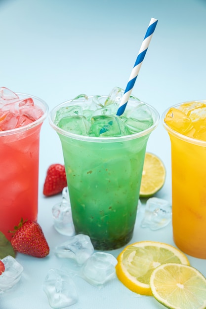 Colorful lemonades with fruits in plastic cups