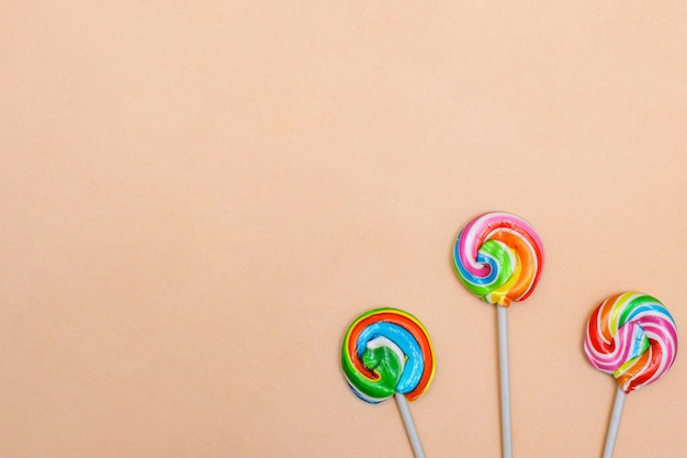 Colorful lollipop candies on cream background with copy space