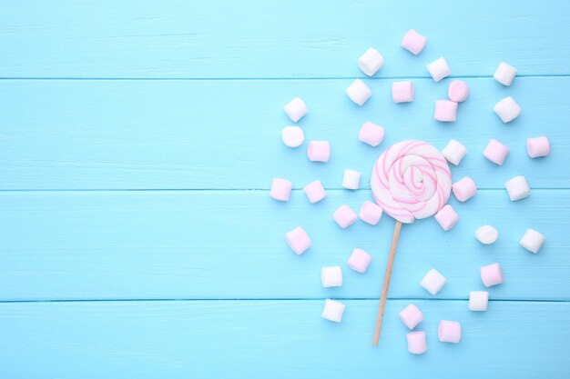 Colorful lollipop and different colored round candy on blue 