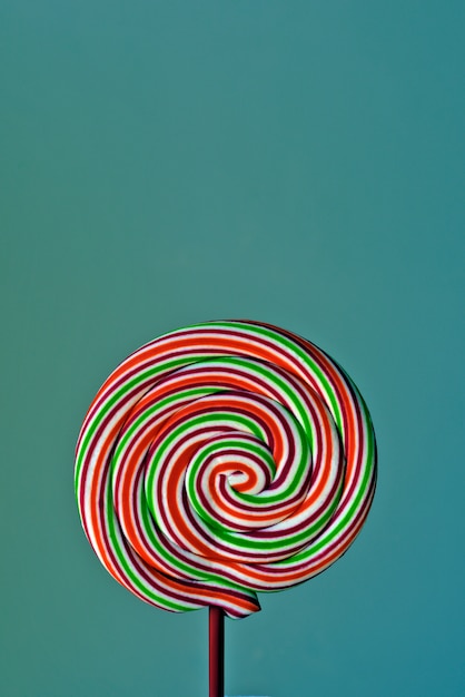 Colorful lollipop in spiral shape on green background