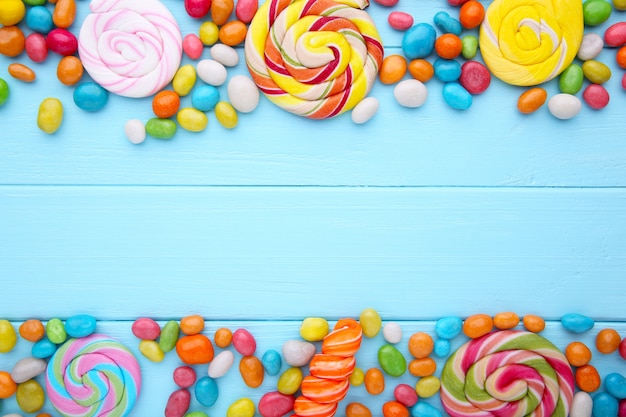 Colorful lollipops and different colored round candy on blue wooden background