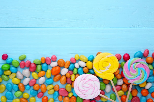 Photo colorful lollipops and different colored round candy on blue