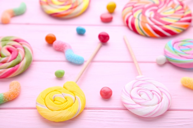 Colorful lollipops and different colored round candy on pink wooden background