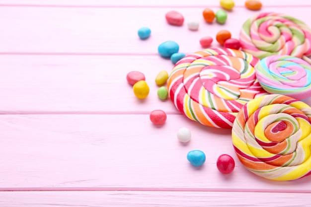 Colorful lollipops and different colored round candy on pink wooden 