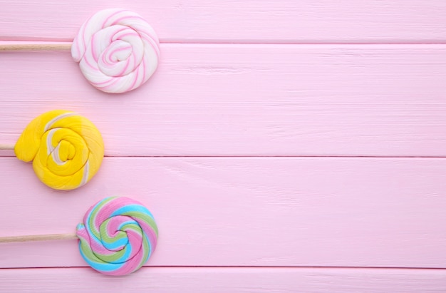 Photo colorful lollipops on pink wooden background, sweets