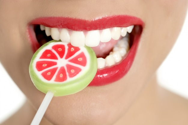 Photo colorful lollypop in perfect woman teeth