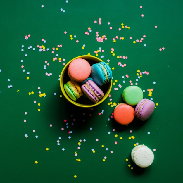 colorful macaron cookies on a green background in a cup