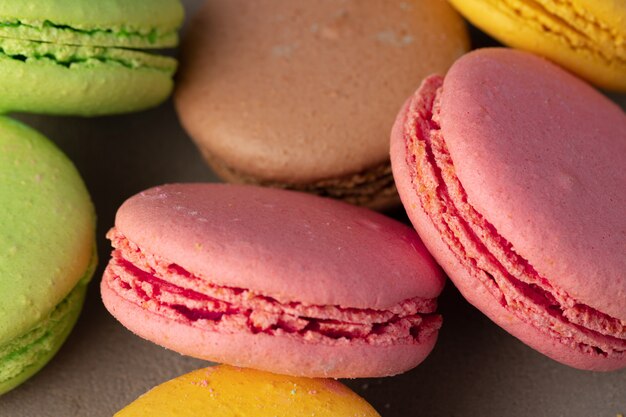 Colorful macaroon cookies on grey surface close up