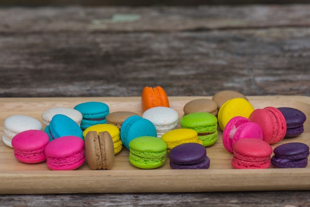 Colorful macaroons in dish on wooden table