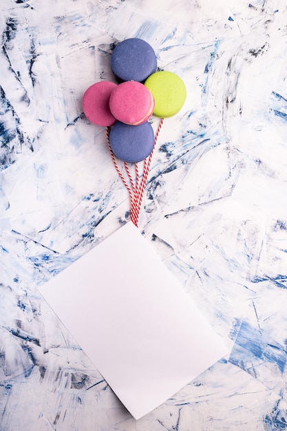 Colorful macaroons in the form of balloons with a tied white sheet for your text a layout for congratulations on copy space