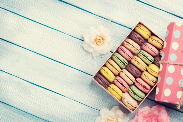 Разноцветные миндальное печенье в подарочной коробке и розы
