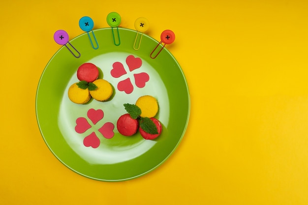 Colorful macaroons on a green plate. Concept for the holiday. Top view. Copy space