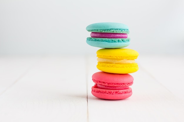 Colorful Macaroons on white wooden background.