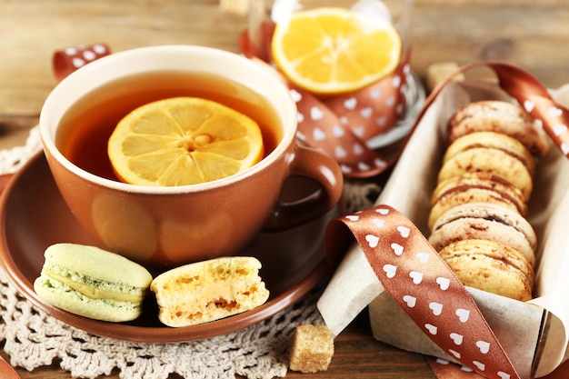 Colorful macaroons with cup of tea on wooden background