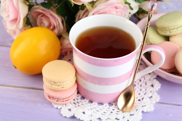 Colorful macaroons with cup of tea on wooden background