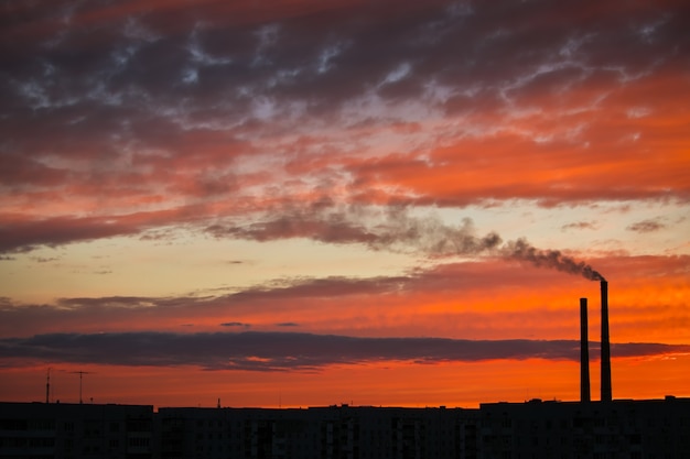 Photo colorful magic sunset. roofs of city houses during sunrise. dark smoke coming from the thermal power plant pipe.