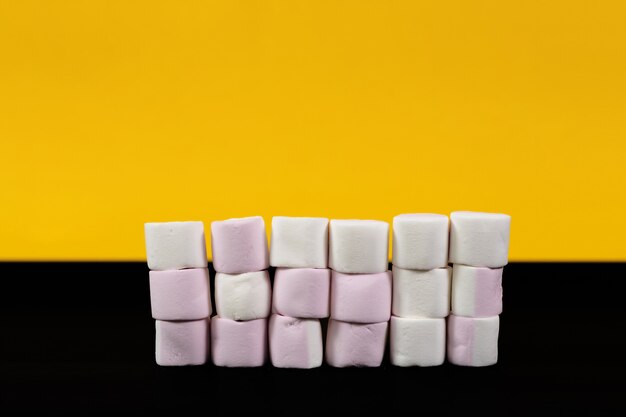 Colorful marshmallow candies on a yellow and black background. close-up