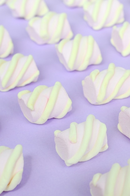 Photo colorful marshmallow laid out on violet paper background. pastel creative textured pattern. perspective macro shot