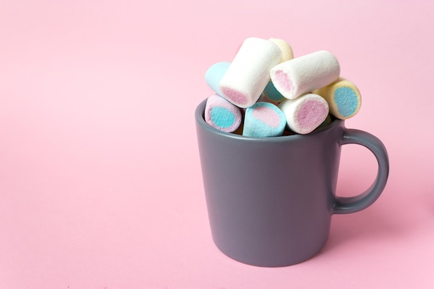 Colorful marshmallows in a cup, over pink background.