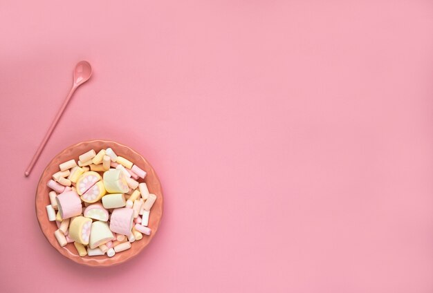 Colorful marshmallows on a pink dish isolated on a pink background. Fluffy marshmallow texture closeup.