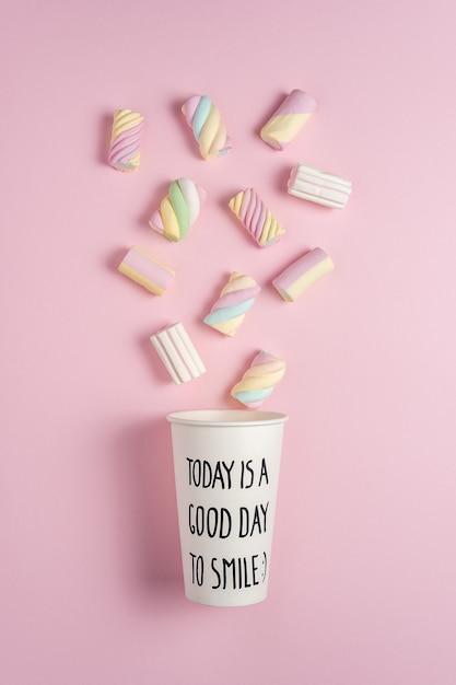 Colorful marshmallows with paper cup on pink background