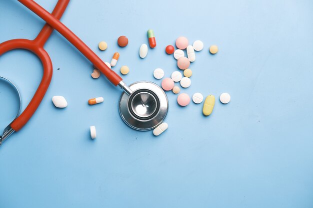 colorful medical pills and stethoscope on blue surface