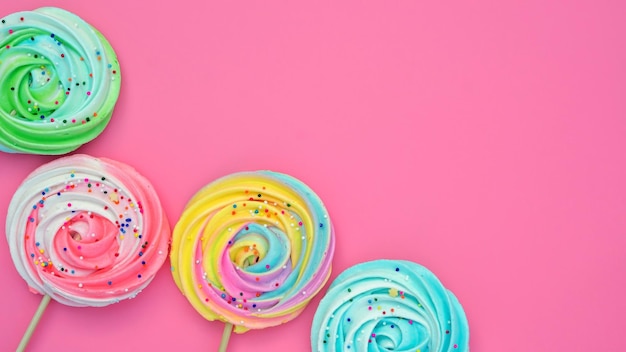 Colorful meringue lollipop on a pink background