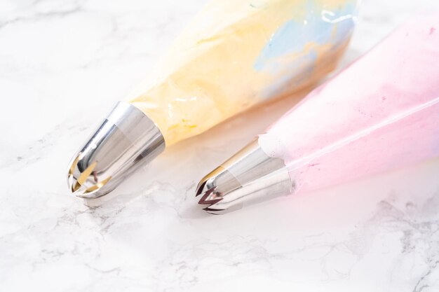 Colorful meringue in piping bags with metal tips.