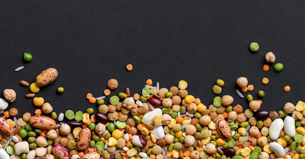 Colorful mixed cereals and legumes ricepeas lentils beans chickpea on black background Top view Copy space