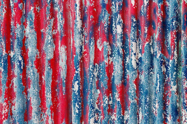 Colorful motley peeled off red and blue paint layers on corrugated zinc coated steel sheet texture