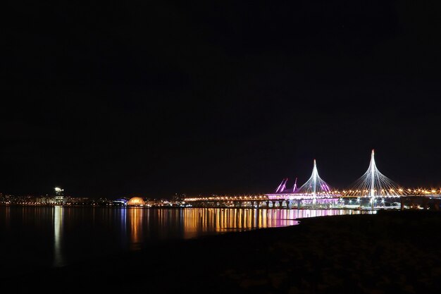 Colorful night cityscape with illuminated bridge over river