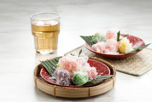 Colorful OngolOngol or Sentiling Steamed Cassava Cake Coating with Grated Coconut Served on Ceramic Plate Copy Space for Text