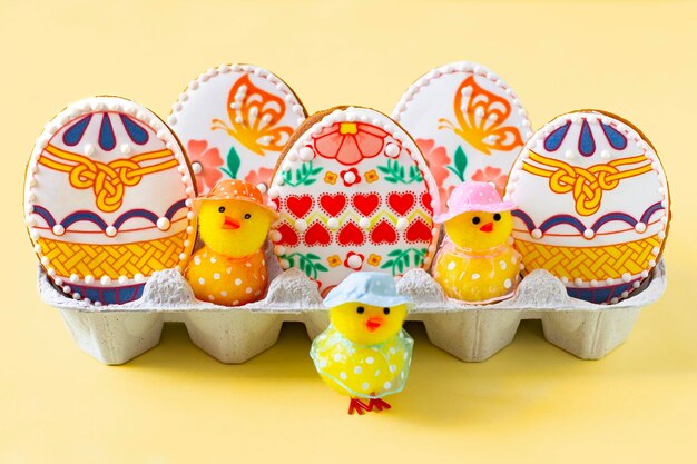Colorful painted easter egg shaped gingerbreads and cute toy chickens