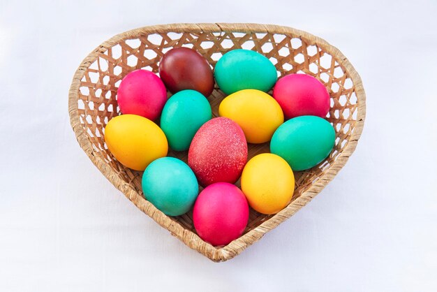 갈색 바구니에 다채로운 페인트 부활절 달걀입니다. 성스러운 정통 기독교 부활절 휴가를 위해 칠해진 다채로운 계란이 있는 하트 형태의 짚으로 만든 바구니.