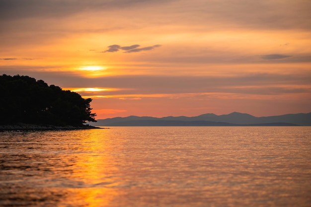 Colorful panoramic sundown with cloudy sky over waterfront on Brac Island Beautiful seascape with calm sea waves Nature landscape Concept of summer holidays at seaside of Croatia