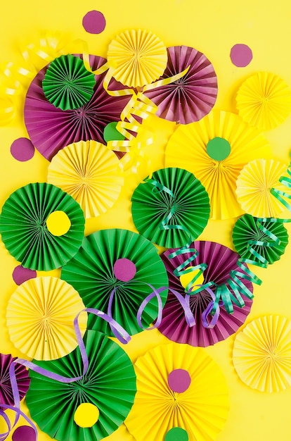 Colorful paper confetti, carnivale mask and colored serpentine on a yellow background