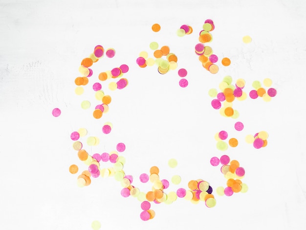 Colorful paper confetti scattered on a white background. Top view