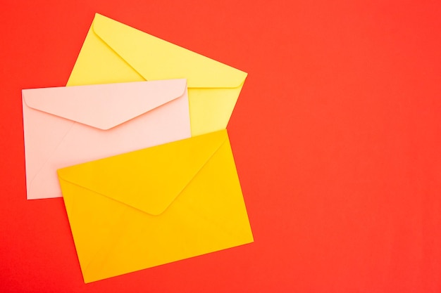 Colorful paper envelopes on red background