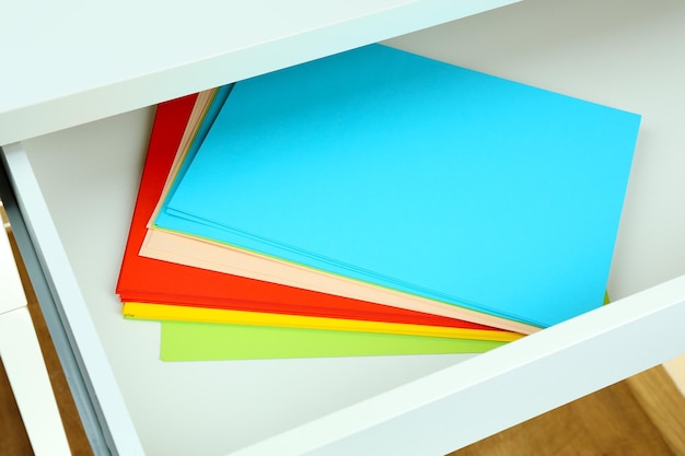 Colorful paper in open desk drawer close up