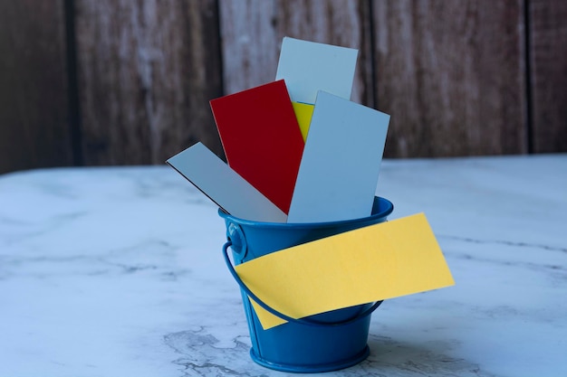 Colorful papers inside of a blue bucket. Space for text. Bucket list concept