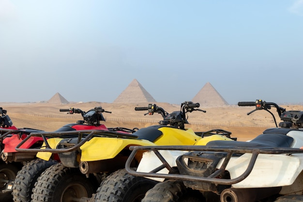 Colorful parked quad bikes atv safari in desert with pyramids in background cairo egypt