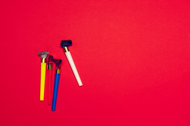 Colorful party blowers or noisemakers on colored background