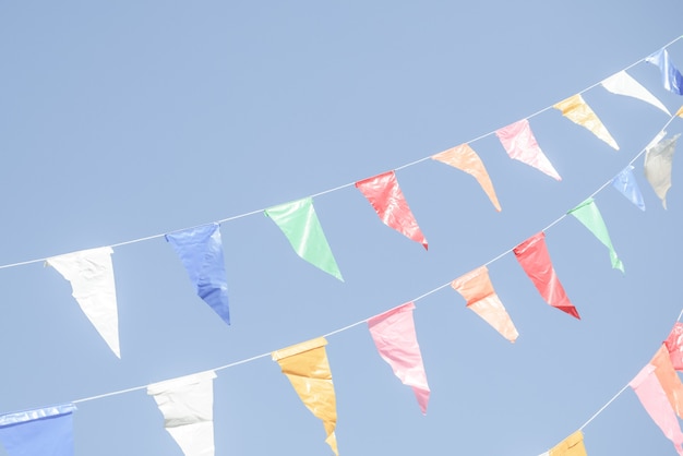 Photo colorful party flags bunting hanging on blue sky for holiday decoration