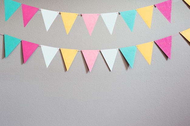 Colorful party flags over cement concrete gray wall texture background pastel birthday colored flags with copy space Holiday concept