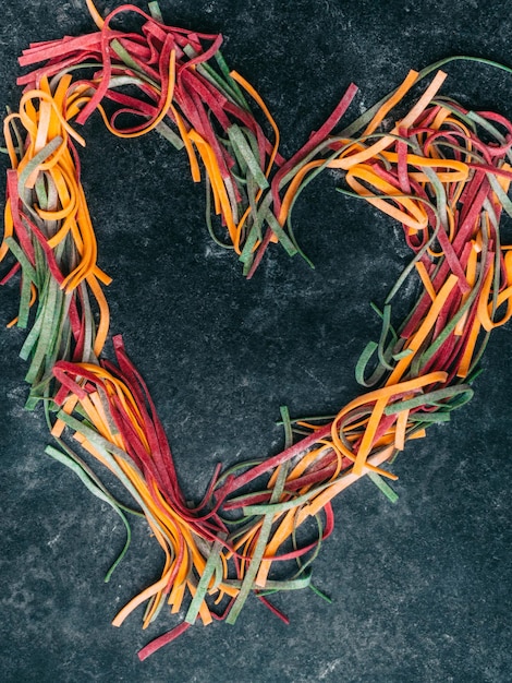 Colorful pasta fettuccine tagliatelle uncooked pasta spaghetti macaroni in heart shape