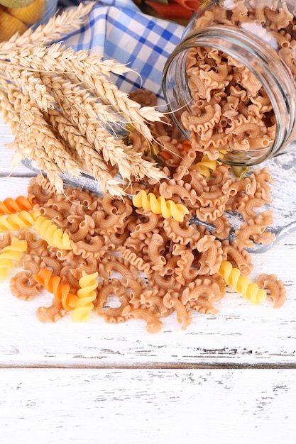 Pasta colorata in barattoli di vetro su una superficie di legno