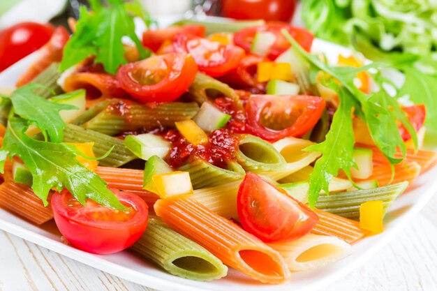 Colorful pasta on a white plate on a wooden