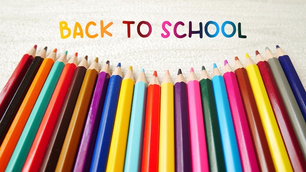 Colorful pencil crayons on a white marble background back to school text with colorful pencil