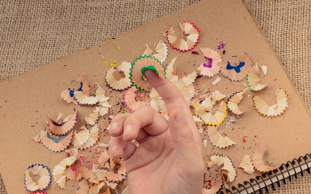 Photo colorful pencil shavings in hand on a notebook